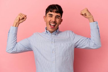 Pembe arka planda izole edilmiş genç melez kadın gücünün sembolü olan kollarla güçlü bir hareket gösteriyor.