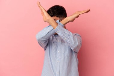 Genç melez adam pembe arka planda izole edilmiş iki kolu çapraz tutuyor, inkar kavramı..