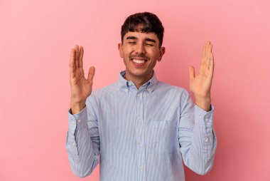 Genç melez adam pembe arka planda izole edilmiş neşeli bir şekilde gülüyor. Mutluluk kavramı.