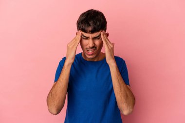 Genç melez adam pembe arka planda izole edilmiş tapınaklara dokunuyor ve başı ağrıyor..