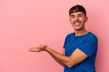 Pembe arka planda izole edilmiş genç bir ırk. Elinde palmiyesinde bir kopyası var..