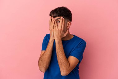 Genç melez adam pembe arka planda izole edilmiş parmaklarıyla gözünü kırp korkmuş ve gergin..