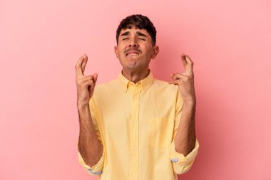 Genç melez adam pembe arka planda izole edilmiş şans dilemek için şans diliyor.