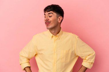 Genç melez adam pembe arka planda izole edilmiş hedeflerine ve amaçlarına ulaşma hayali kuruyor.