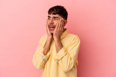 Genç melez adam pembe arka planda izole edilmiş korkmuş ve korkmuş..