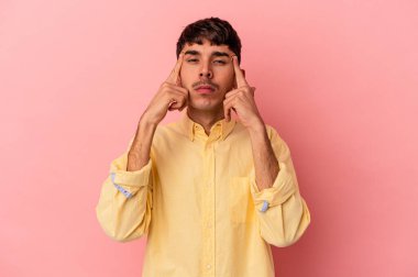 Pembe arka planda izole edilmiş genç melez bir adam bir göreve odaklanmış, işaret parmaklarını işaret ediyor..