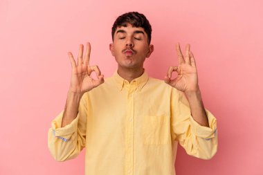 Genç melez adam pembe arka planda izole edilmiş sıkı çalışma gününden sonra rahatlıyor, yoga yapıyor..