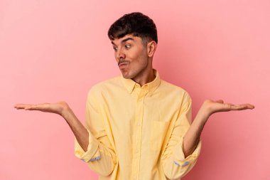 Genç melez adam pembe arka planda izole edilmiş. Kafası karışmış ve omuz silkiyor. Kopya alanını tutmak için..