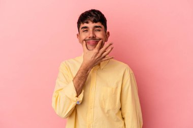 Genç melez adam pembe arka planda izole edildi. İki seçenek arasında şüpheye düştü..