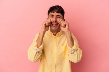 Genç melez adam, pembe arka planda izole edilmiş sızlanıyor ve ağlıyordu..