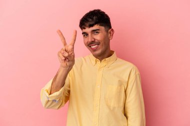 Genç melez adam pembe arka planda izole edilmiş iki numarayı parmaklarıyla gösteriyor..