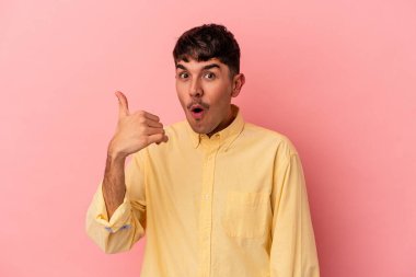 Genç melez adam pembe arka planda izole edilmiş bir şekilde bir şeylere gülüyor, ağızlarını ellerle kapatıyor..