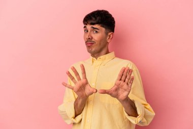 Genç melez adam, pembe arka planda izole edilmiş, tiksinti gösteren birini reddediyor..