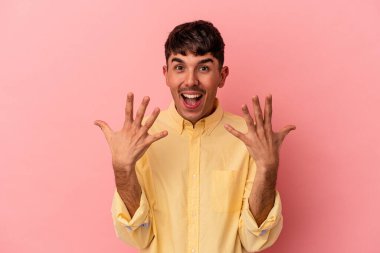 Genç melez adam pembe arka planda izole edilmiş. Elleriyle on numarayı gösteriyor..