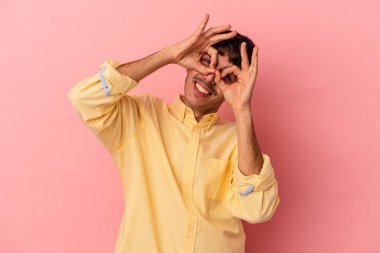 Genç melez adam pembe arka planda izole edilmiş, gözlerinde sorun yok işareti var.