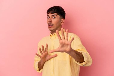 Genç melez adam pembe arka planda izole edildi. Yakın bir tehlike nedeniyle şoka uğruyor.