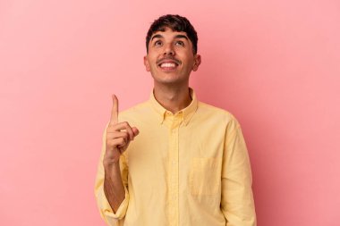 Pembe arka planda izole genç melez adam iki ön parmağı da boş bir alan gösteriyor..