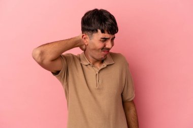 Genç melez adam pembe arka planda izole edilmiş. Stres yüzünden boynu ağrıyor, masaj yapıyor ve elle dokunuyor..