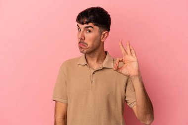 Pembe arka planda soyutlanmış genç melez bir adam göz açıp kapayıncaya kadar iyi bir el hareketi yapıyor..