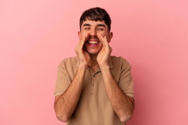 Genç melez adam pembe arka planda izole edilmiş. Dedikodu yapıyor, bir şeyleri bildiriyor..