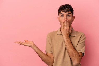 Pembe arka planda izole edilmiş genç melez adam, avuç içinde kopya alanı tutmaktan etkilenmiş..