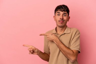 Pembe arka planda izole edilmiş genç melez adam işaret parmağıyla fotokopi alanını işaret ederek şok oldu..
