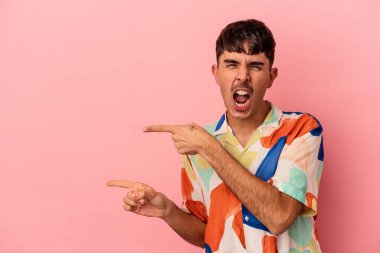 Pembe arka planda izole edilmiş genç melez adam işaret parmağıyla fotokopi alanını işaret ederek heyecan ve arzuyu ifade ediyor..