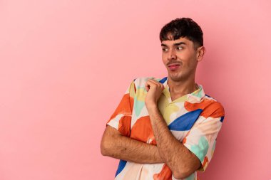 Genç melez adam pembe arka planda izole edilmiş kafası karışmış, kuşkulu ve güvensiz hissediyor..