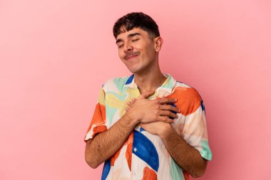Pembe arka planda izole edilmiş genç melez adam, avuçlarını göğsüne bastıran dostane bir ifadeye sahiptir. Aşk konsepti.