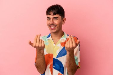 Genç melez adam pembe arka planda izole edilmiş seni işaret ediyor sanki davet ediyormuş gibi..