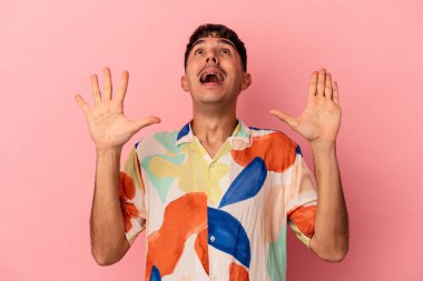 Genç melez adam pembe arka planda izole edilmiş gökyüzüne haykırıyor, yukarı bakıyor, hayal kırıklığına uğramış..