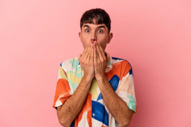 Pembe arka planda izole edilmiş genç melez adam elleriyle ağzını kapatırken şok oldu..