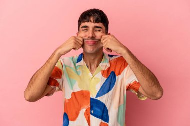 Genç melez adam pembe arka planda izole edildi. İki seçenek arasında şüpheye düştü..