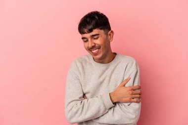 Genç melez adam pembe arka planda izole edilmiş gülüyor ve eğleniyor..