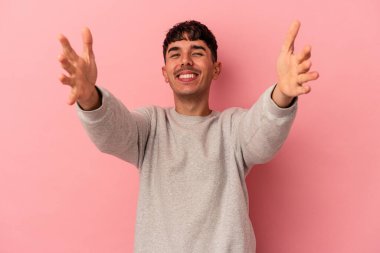 Pembe arka planda yaşayan genç melez bir adam zaferi ya da başarıyı kutluyor, şaşırıyor ve şok oluyor..