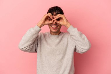 Genç melez adam pembe arka planda izole edilmiş, gözlerinde sorun yok işareti var.