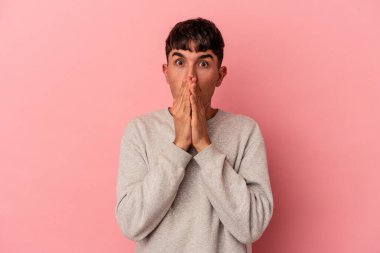 Genç melez adam pembe arka planda izole edilmiş ağzı kapalı ve elleri endişeli görünüyor..