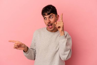 Genç melez adam pembe arka planda izole edilmiş farklı kopya alanlarını gösteriyor, birini seçiyor, parmaklarıyla gösteriyor..