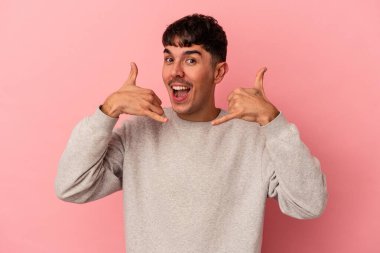 Pembe arka planda izole edilmiş genç melez bir adam parmaklarıyla bir cep telefonu çağrısı gösteriyor..