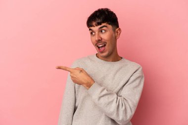 Pembe arka planda soyutlanmış genç melez adam. Gülümsüyor, neşeli ve keyifli görünüyor..