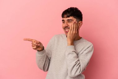 Genç melez adam pembe arka planda izole edilmiş. Dedikodu yapıyor, bir şeyleri bildiriyor..