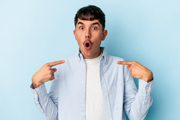 Молодой смешанной расы человек изолирован на синем фоне указывает вниз с пальцами, позитивное чувство.