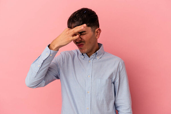 Young mixed race man isolated on pink background having a head ache, touching front of the face.