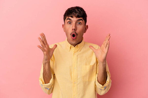 Молодой смешанной расы человек изолирован на розовом фоне удивлен и шокирован.