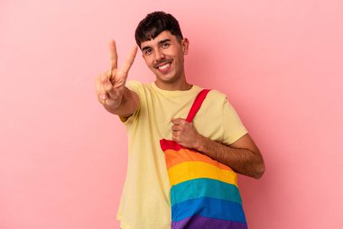 LGTB çanta giyen genç melez adam pembe arka planda izole edilmiş.