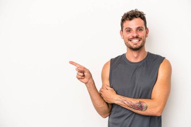 Beyaz arka planda izole edilmiş genç beyaz adam işaret parmağıyla işaret ederek gülümsüyor..