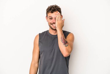 Beyaz arka planda izole edilmiş genç beyaz bir adam yüzünün yarısını palmiye ile örterek eğleniyor..