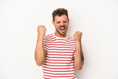 Beyaz arka planda izole edilmiş genç beyaz adam tasasız ve heyecanlı bir şekilde tezahürat yapıyor. Zafer konsepti.