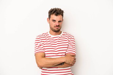 Beyaz arka planda izole edilmiş genç beyaz adam alaycı bir ifadeyle kameraya bakıyor..