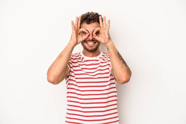 Beyaz arka planda izole edilmiş genç beyaz bir adam gözlerinde sorun olmadığını gösteriyor.